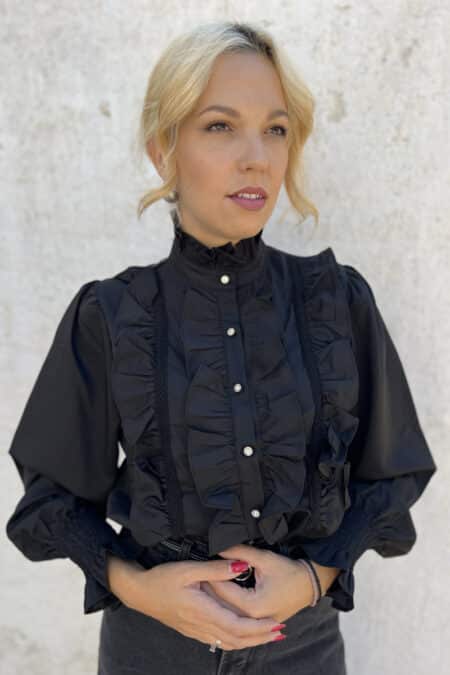 Γυναικείο πουκάμισο με βολάν σε μαύρο χρώμα, με κουμπιά από στρας και balloon μανίκια με λάστιχο-σφηκοφωλιά.